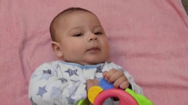 Dilini koyarak ve bacakları ile tekme diş çıkarma oyuncak ile pembemsi havlu üzerinde sırtında döşeme şirin ağaç aylık bebeğim