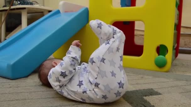 树月大的男婴在后院的地毯上横穿双腿 而塑料游戏屋则在背景中 — 图库视频影像