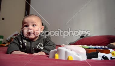 Kırmızı yatak örtüsü üzerinde karın vakit geçiriyor ve komik surat - erken geliştirme kavramı şirin dört aylık erkek bebek