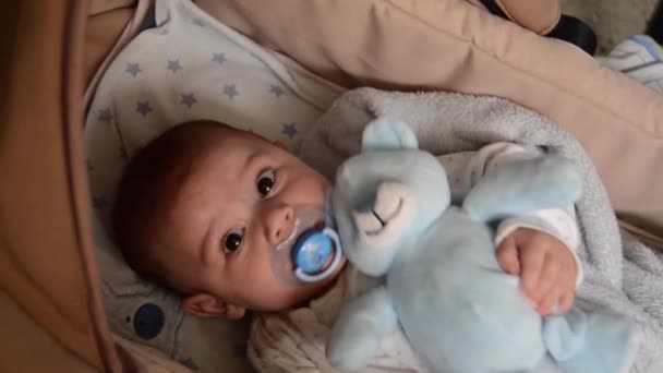 Cute 3 months old baby boy making funny faces in baby carry cot — Stock Video