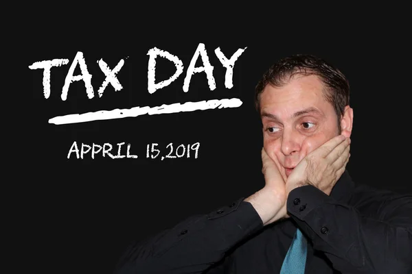 business man stressed because of coming tax day - chalk words on black board - tax day concept