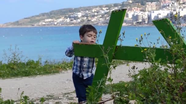 Mignon deux ans bébé garçon escalade sur vert cassé table dans le parc mer en arrière-plan — Video