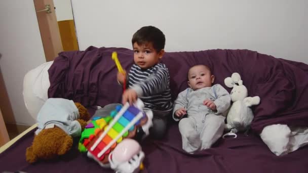 Dois anos de idade e 4 meses de idade meninos brincando na cama roxa com xilofone e brinquedos macios — Vídeo de Stock