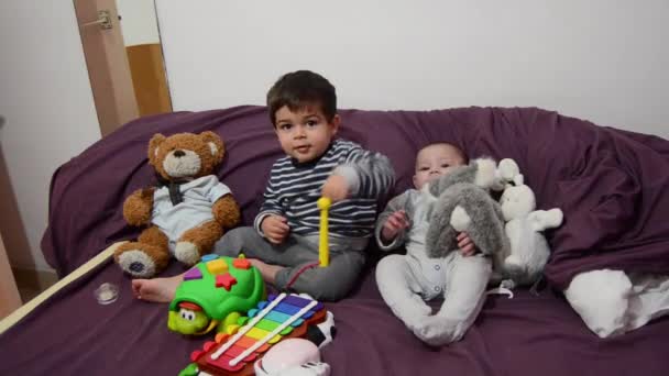 Niños de dos años y 4 meses jugando en ropa de cama púrpura con xilófono y juguetes blandos — Vídeo de stock