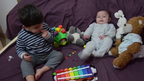 Dois anos de idade e 4 meses de idade meninos brincando na cama roxa com xilofone e brinquedos macios — Vídeo de Stock