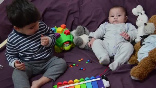 Dois anos de idade e 4 meses de idade meninos brincando na cama roxa com xilofone e brinquedos macios — Vídeo de Stock