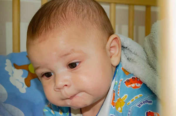 かわいい 4 ヶ月古い男の子ベビーベッドで面白い顔を作る — ストック写真