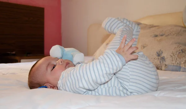 Carino 4 mesi vecchio bambino sdraiato sul letto e giocare con le gambe — Foto Stock