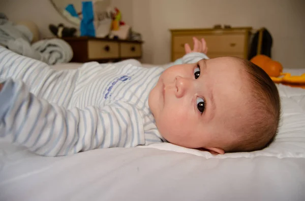 Милий 4-місячний хлопчик лежить на ліжку і дивиться в камеру — стокове фото