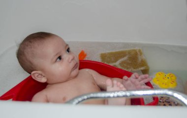 Banyoda büyük küvet FITH köpük içine kırmızı plastik tabak içinde şirin 4 aylık erkek bebek