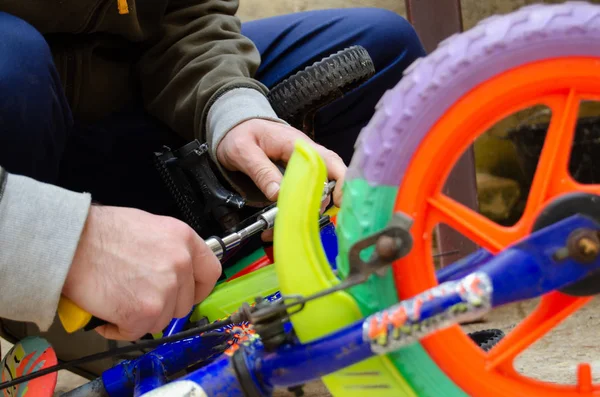 Чоловік закріплює педалі на дитячому барвистому велосипеді — стокове фото