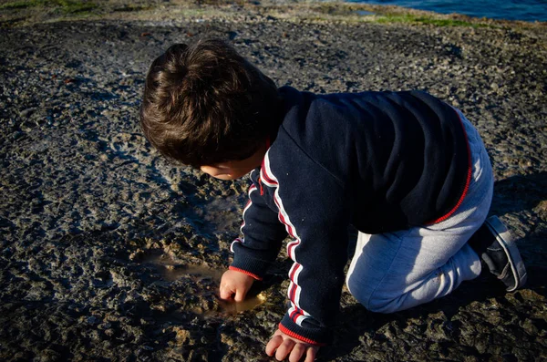 Lindo niño de dos años jugando con agua en el camino de piedra —  Fotos de Stock