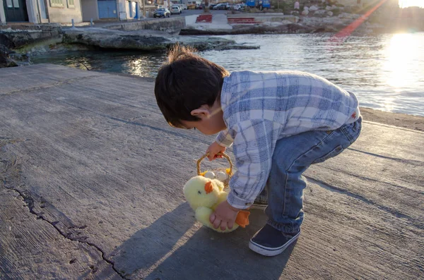 Carino due anni bambino giocare con piccolo giocattolo di pollo e cesto con due uova di Pasqua sul mare doc — Foto Stock