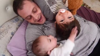 Baba ve iki oğul, Bebek ve Toddler, yatakta birlikte oynuyor