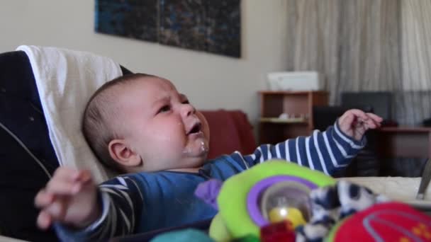 Hungry six months old baby crying for food in the highchair. Mother feeding baby — Stock Video