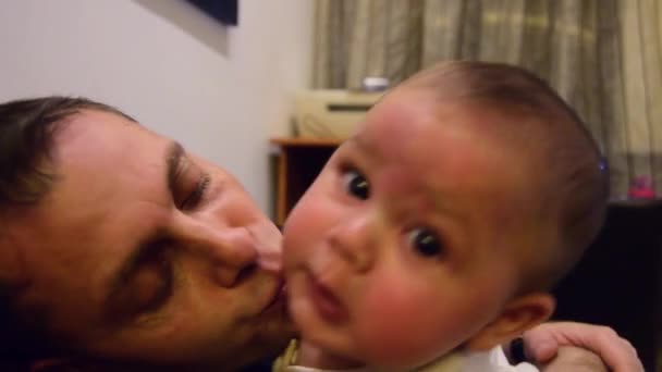 Father is kissing six months old baby boy but he doesnt enjoy it. Father and son spending some quality time together — Stock Video