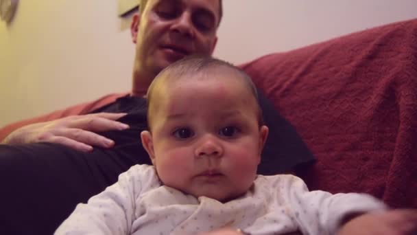 Father is immitating sounds that his six months old baby boy is making while tickling his feet. Baby is making funny faces and kicking with his feet — Stock video