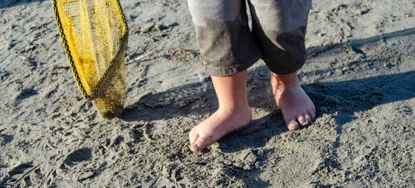 Söt två år gammal pojke leker med fiske nät på solig dag på havet stranden — Stockfoto