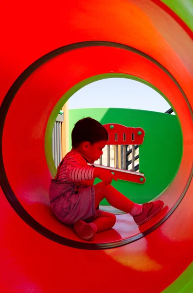 Söt två år gammal pojke playig i barnens lekplats utomhus i tunneln — Stockfoto