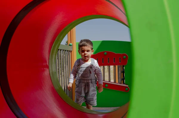 可爱的两岁男孩在儿童游乐场在隧道户外玩耍 — 图库照片