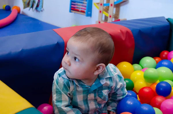 Lindo niño de seis meses jugando con bolas de colores en el cuidado de niños —  Fotos de Stock