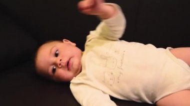 Sevimli altı aylık bebek çocuk ayakları ile tekme ve sırtından yan açmak için çalışıyor