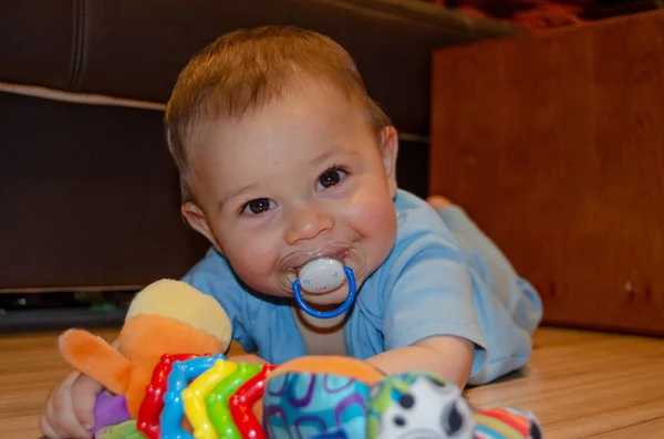 Uroczy sześciomiesięczny chłopiec bawią się na Flor z zabawką z ząbykami, wczesnym rozwojem i koncepcją ząbkowanie — Zdjęcie stockowe