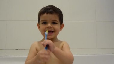 sevimli iki yaşındaki çocuk küvette dişlerini fırçalama