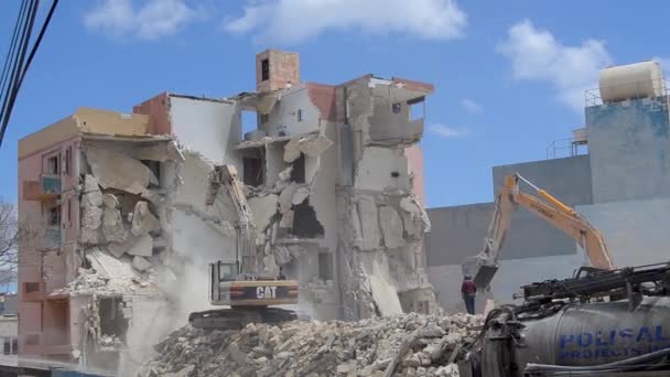 Qawra, Malta 16 de mayo de 2019 - Segundo día de demolición del antiguo hotel Qawra Inn - demoler edificios con excavadoras y supervisores no lleva ropa protectora ni cascos — Vídeo de stock