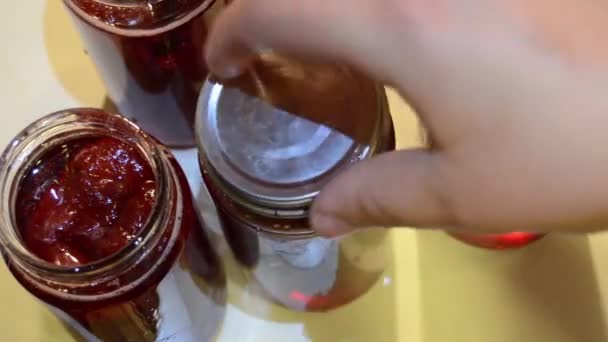 Mujer pone mermelada de fresa hecha a mano en tarro — Vídeo de stock
