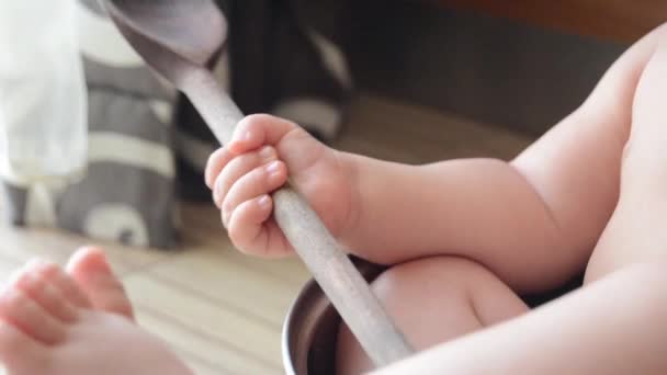 かわいい6ヶ月の赤ちゃんの男の子は、調理鍋と木製のスプーンをクローズアップで遊んで — ストック動画