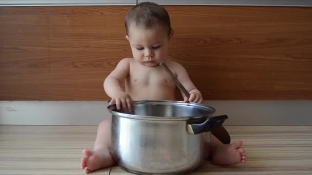Милий шестимісячний хлопчик грає з кухонним горщиком і дерев'яною ложкою — стокове відео