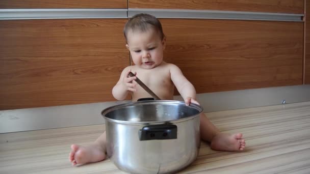 Cute zes maanden oude baby jongen spelen met koken pot en houten lepel — Stockvideo