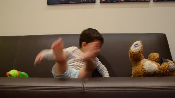 Cute two years old boy watching tv with his teddy bear - putting teddy to sit properly — Stock Video