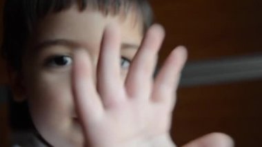 Çocuk kamera önünde elini koyarak