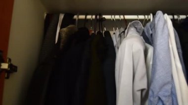 bir Mans wardroobe içinde, askıları üzerinde gömlek giysileri