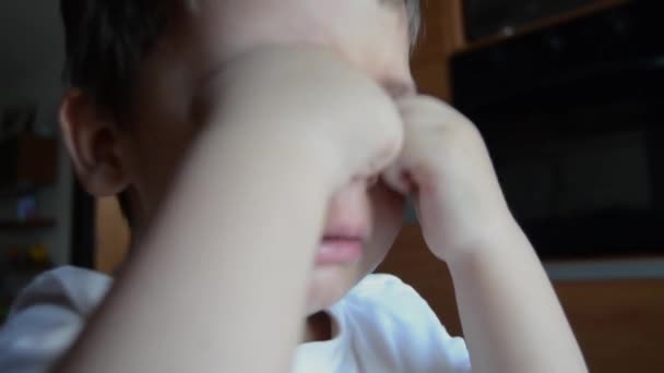Грустный и уставший двухлетний мальчик плачет и потирает глаза — стоковое видео