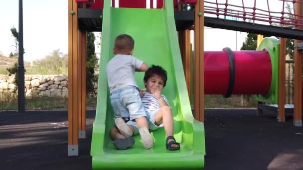 Bröder som leker på lekplatsen. Att glida ner för rutschkanan och klättra Slow motion — Stockvideo