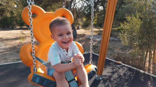 Adorable niño en un columpio con una gran sonrisa en su cara —  Fotos de Stock