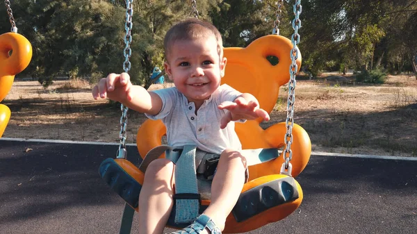 Adorable niño en un columpio con una gran sonrisa en su cara —  Fotos de Stock