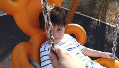 Sevimli küçük çocuk somurtkan yüzüyle salıncakta