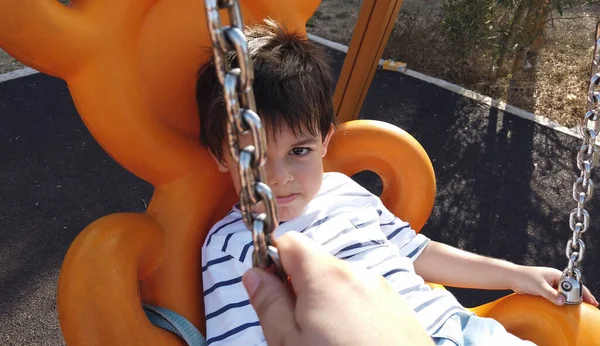 Sevimli küçük çocuk somurtkan yüzüyle salıncakta