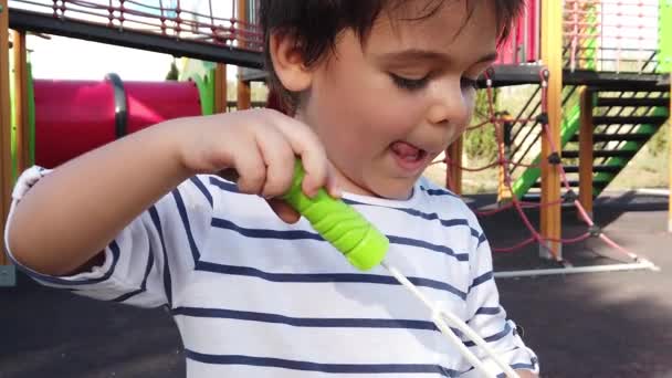 Zdjęcie portretowe chłopca z przedszkola robiącego bańki mydlane po raz pierwszy na pustym placu zabaw. Zwolniony ruch — Wideo stockowe