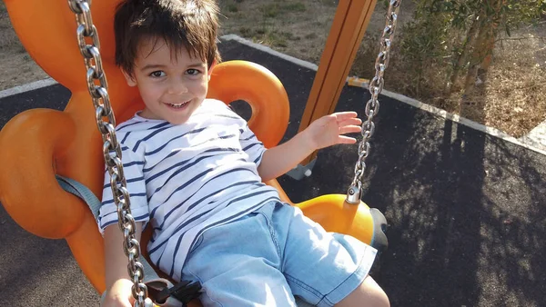 Adorable niño, preescolar balanceándose en el columpio en un parque vacío —  Fotos de Stock