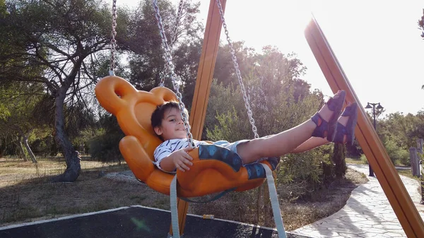 Adorable niño, preescolar balanceándose en el columpio en un parque vacío — Foto de Stock