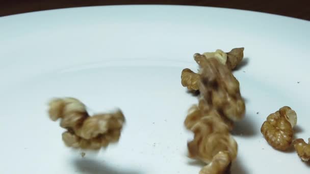 Close up, walnoten faling op de witte plaat in slow motion — Stockvideo