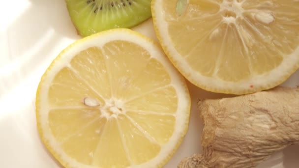 Cortes de jengibre, limón y kiwi en el plato blanco. revelador tiro — Vídeo de stock