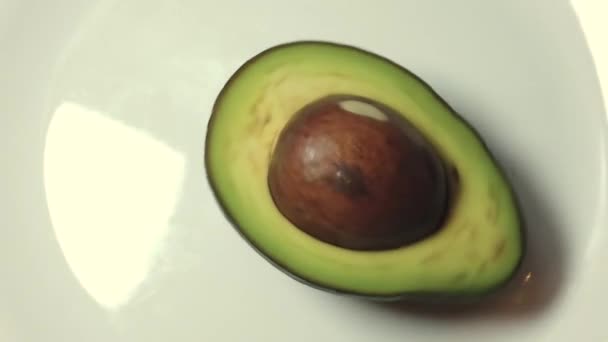 Metà dell'avocado che gira sulla piastra bianca al rallentatore — Video Stock