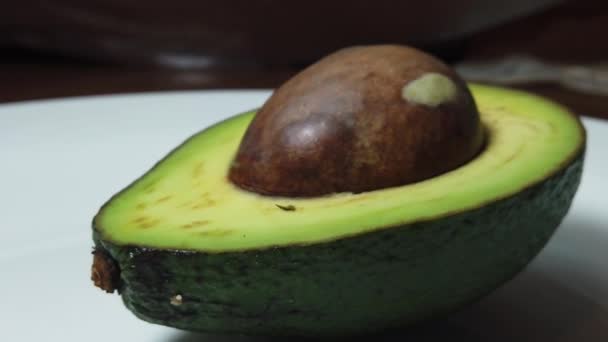 De helft van de avocado spuwt op de witte plaat — Stockvideo