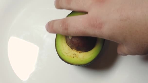 Kéz spinning avokádó a fehér tányéron. Lassú mozgás. — Stock videók